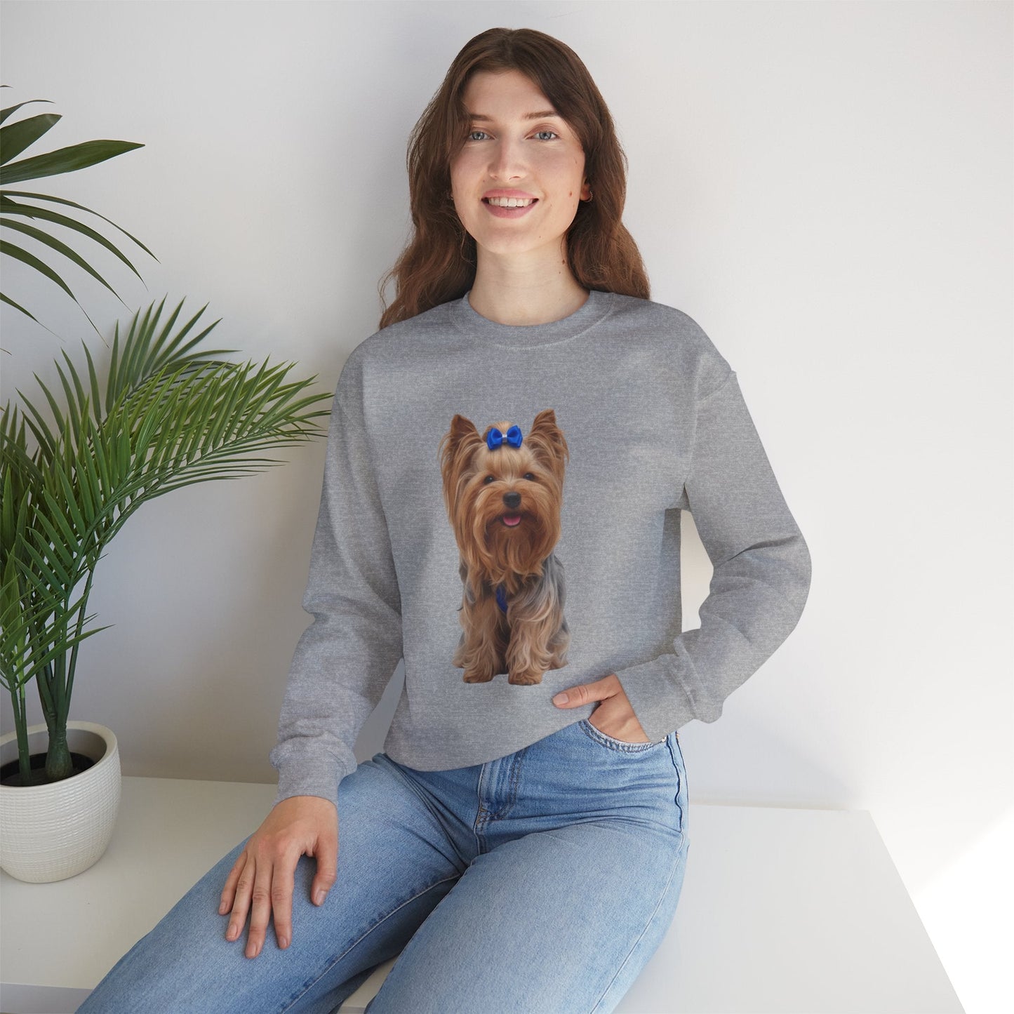 Ragazza seduta che indossa Felpa Girocollo Unisex AKYCO con ritratto di Aky sul davanti e vestibilità comoda, ideale per amanti degli Yorkshire Terrier