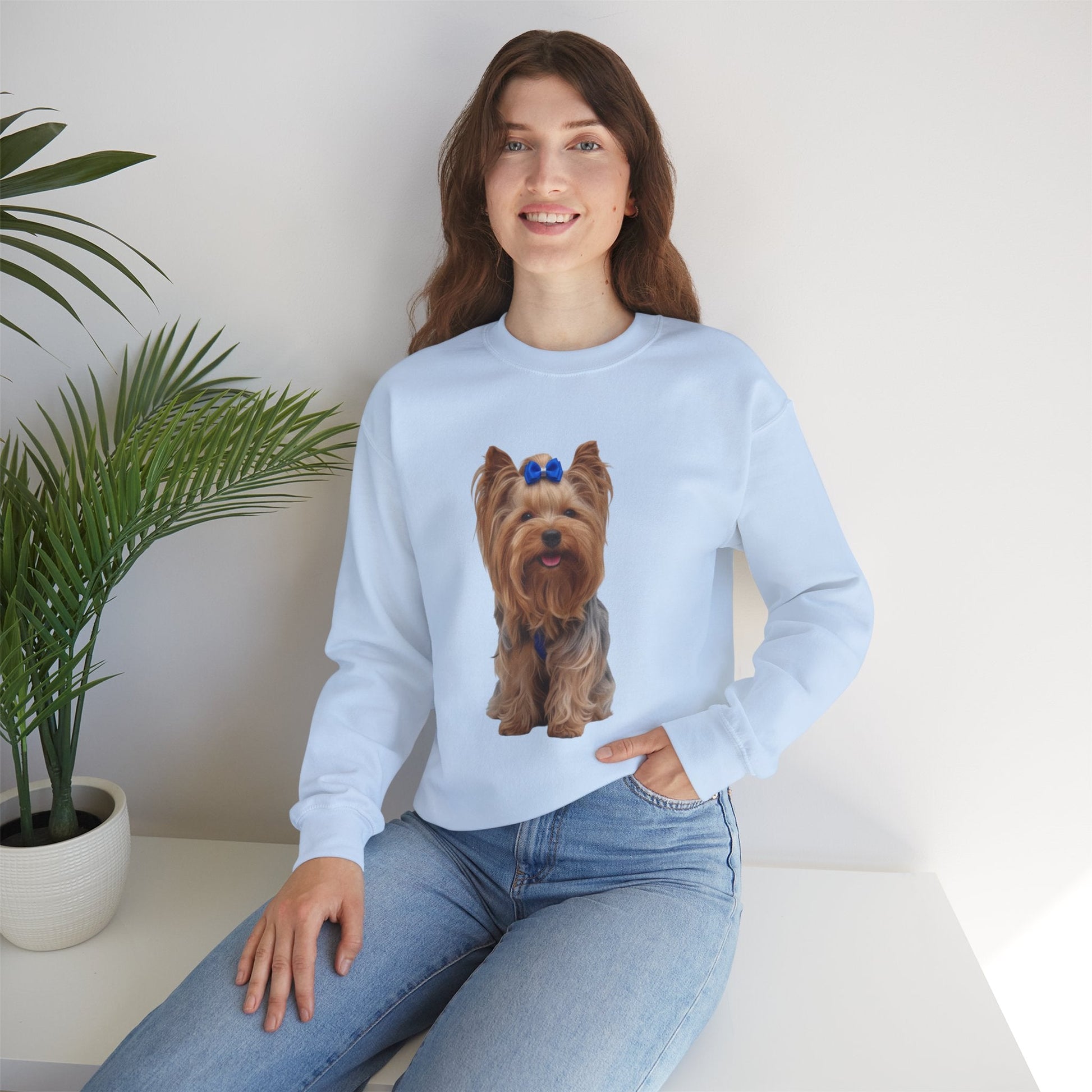 Ragazza seduta che indossa Felpa Girocollo Unisex AKYCO con ritratto di Aky sul davanti e vestibilità comoda, ideale per amanti degli Yorkshire Terrier