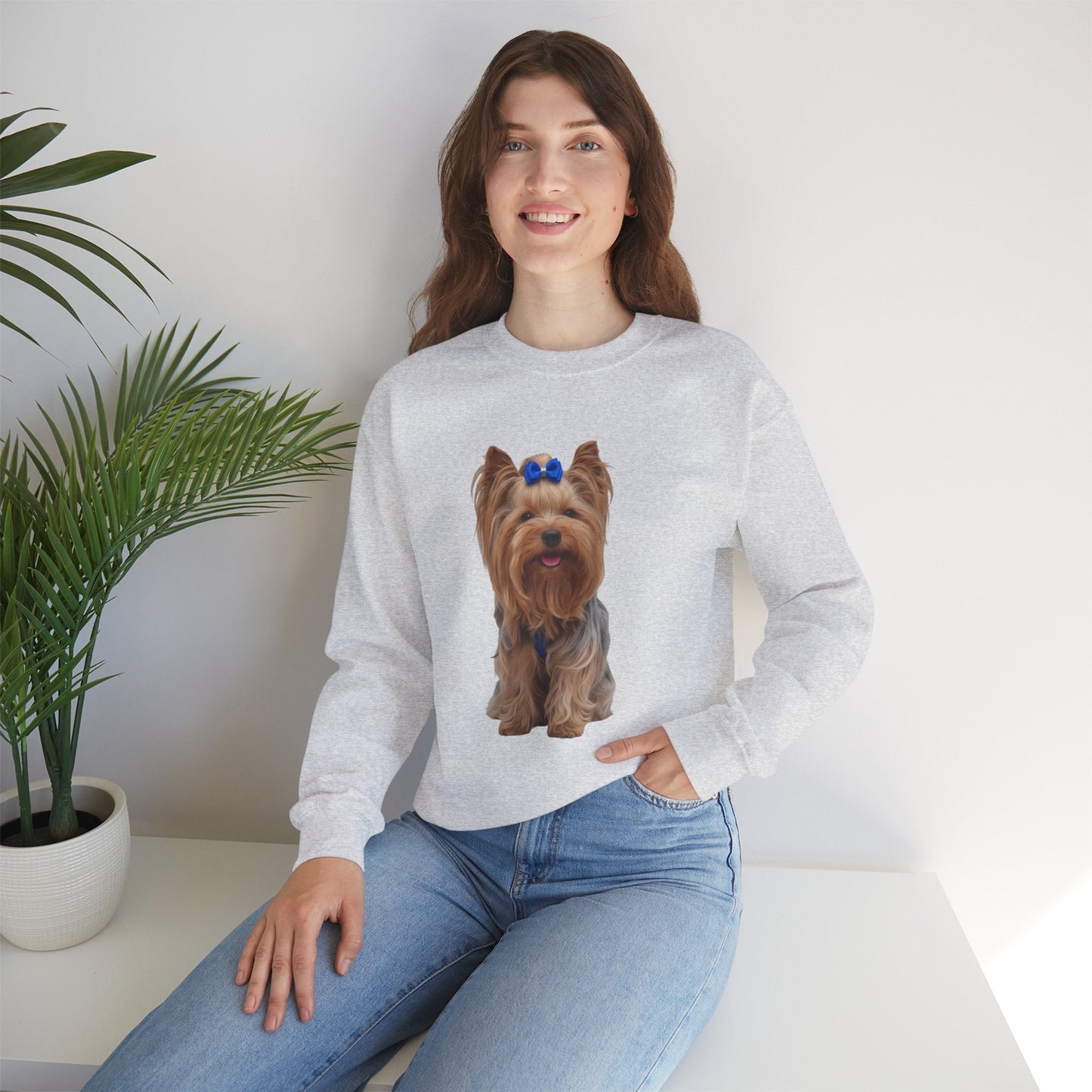 Ragazza seduta che indossa Felpa Girocollo Unisex AKYCO con ritratto di Aky sul davanti e vestibilità comoda, ideale per amanti degli Yorkshire Terrier